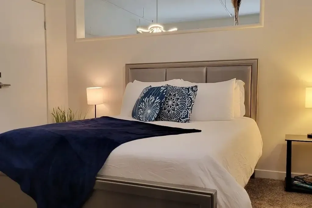 A bed with white sheets and pillows on it.